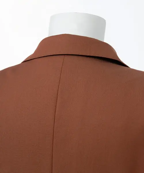 Ensemble Pure Elegance orange brique avec veste croisée à double boutonnage, pantalon assorti et chemise blanche à grand col pointu.