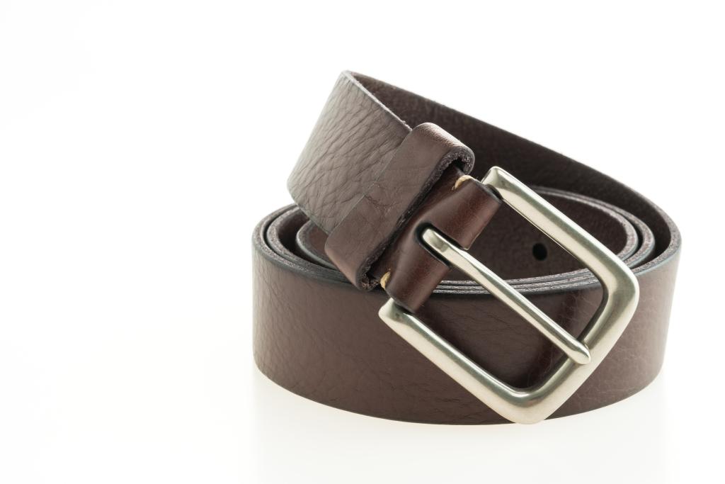 Ceinture en cuir marron enroulée sur fond blanc, boucle métallique argentée, finition lisse et élégante.