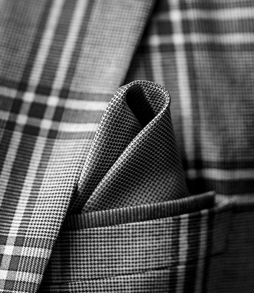 PureElegance : gros plan d’un costume à motif carreaux, avec pochette soigneusement pliée, mettant en valeur la texture du tissu et les finitions.